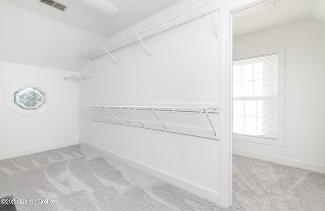 walk in closet featuring vaulted ceiling and light colored carpet