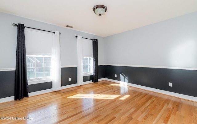 spare room featuring visible vents, wood finished floors, a wealth of natural light, and baseboards