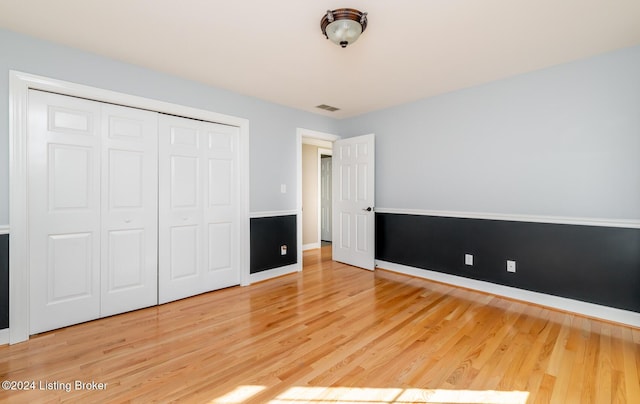 unfurnished bedroom with baseboards, a closet, visible vents, and wood finished floors