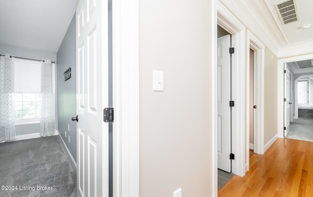 hall with wood-type flooring and ornamental molding