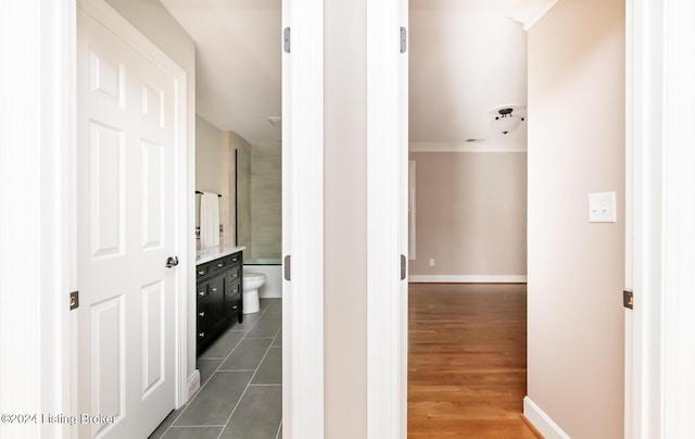 corridor featuring ornamental molding, dark wood-type flooring, and baseboards