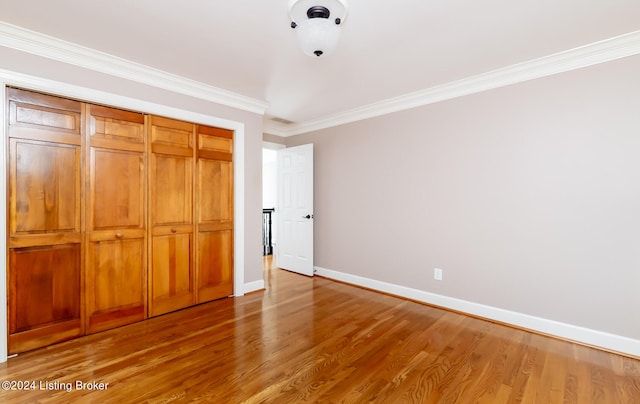 unfurnished bedroom with crown molding, hardwood / wood-style flooring, and a closet