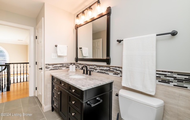 bathroom with a wainscoted wall, tile walls, toilet, vanity, and tile patterned flooring