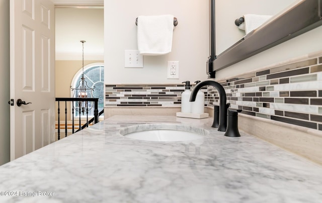 interior details with crown molding, decorative backsplash, a notable chandelier, and vanity