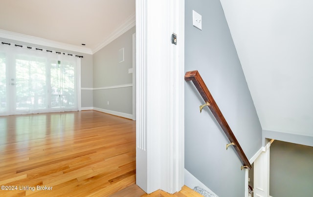 stairs featuring ornamental molding, hardwood / wood-style flooring, and vaulted ceiling