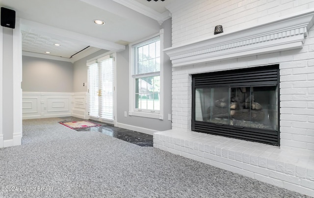 interior space featuring a wainscoted wall, crown molding, a brick fireplace, a decorative wall, and recessed lighting