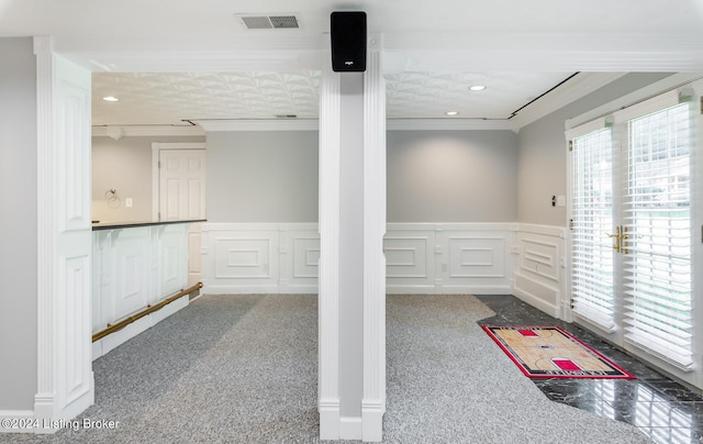 interior space with carpet floors, ornamental molding, wainscoting, and visible vents