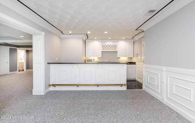 kitchen with white cabinetry, crown molding, and dark carpet