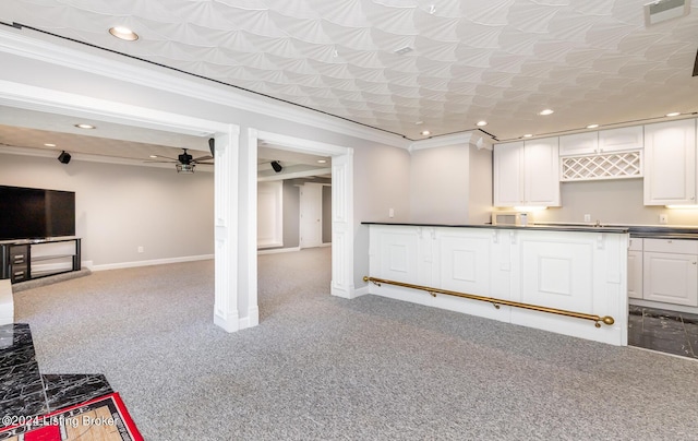 kitchen with carpet, ornamental molding, open floor plan, white cabinetry, and baseboards