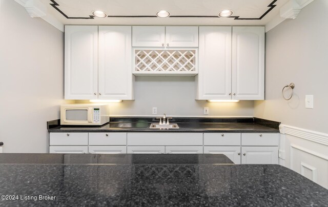 kitchen featuring sink, white cabinetry, and dark stone countertops