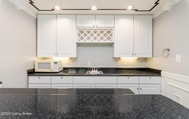 kitchen featuring white microwave, recessed lighting, a sink, and white cabinets