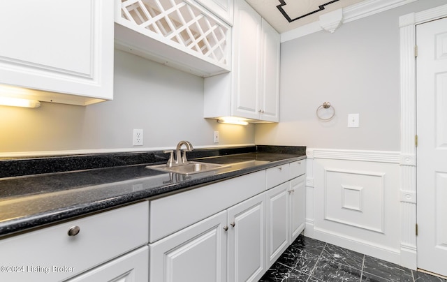 kitchen with a wainscoted wall, marble finish floor, a sink, and white cabinets