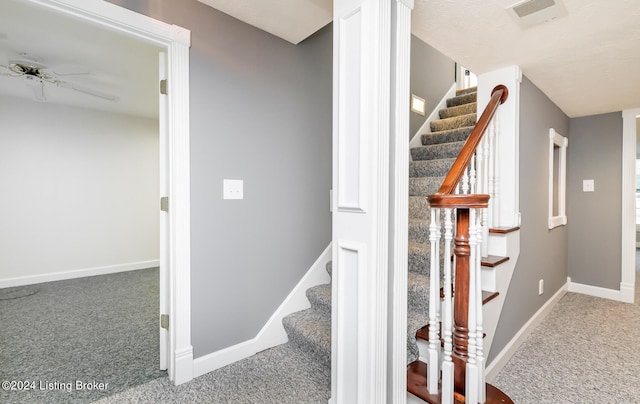 stairway with ceiling fan and carpet