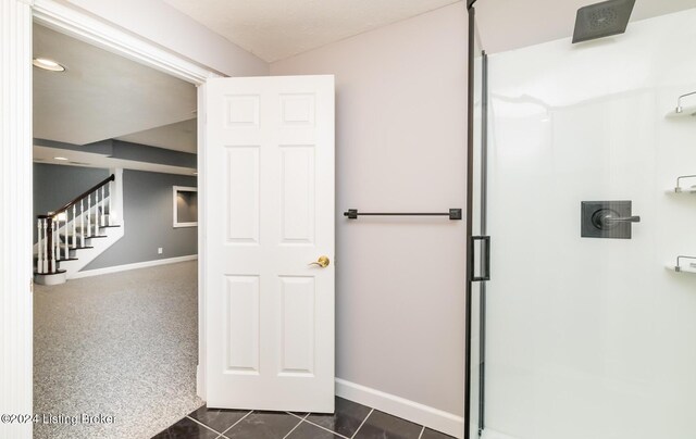 bathroom with a shower with door and tile patterned flooring