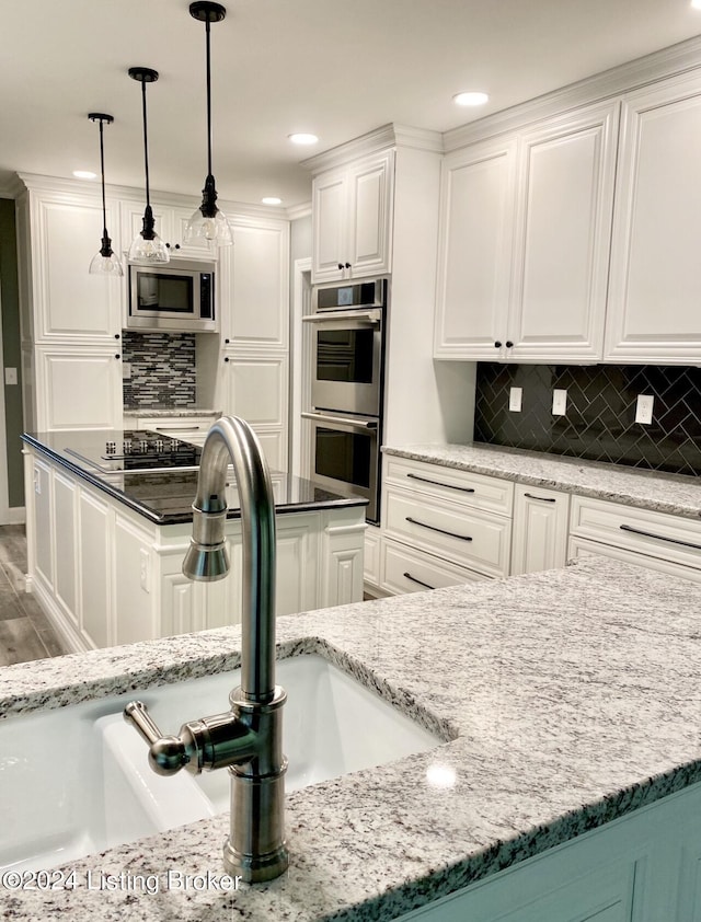 kitchen with dark stone countertops, appliances with stainless steel finishes, white cabinets, and a sink