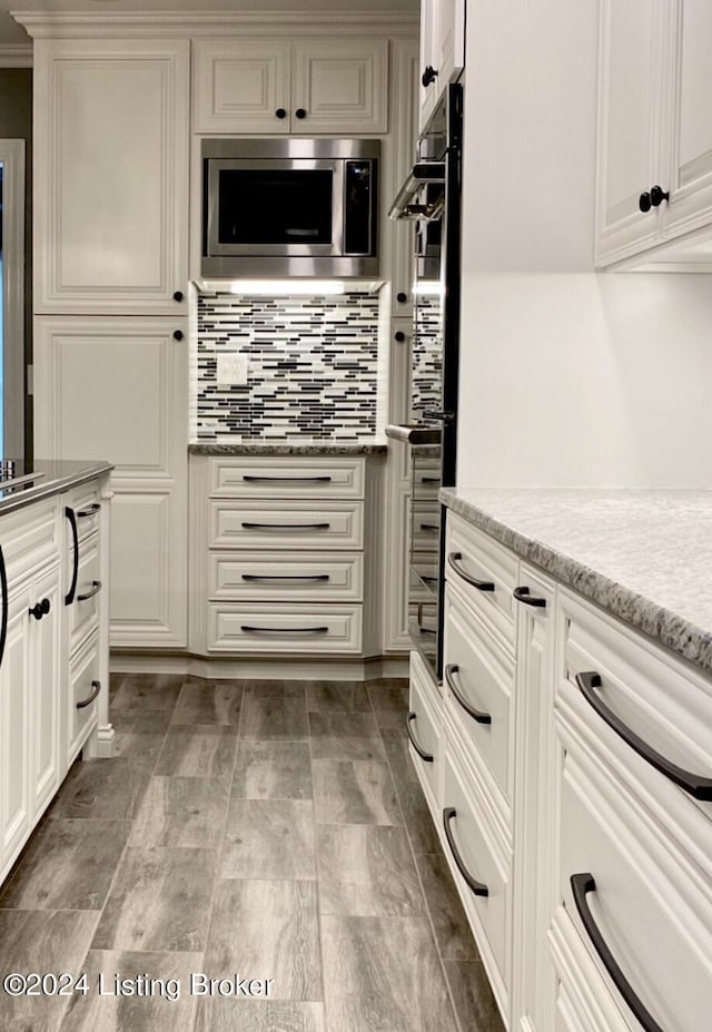 kitchen featuring light countertops, white cabinets, stainless steel microwave, and backsplash