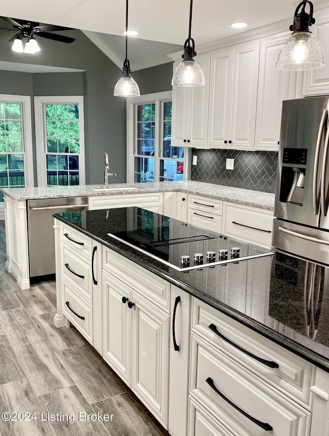 kitchen featuring appliances with stainless steel finishes, white cabinetry, a sink, and dark stone countertops