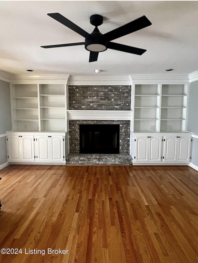 unfurnished living room featuring ceiling fan, a fireplace, wood finished floors, and baseboards