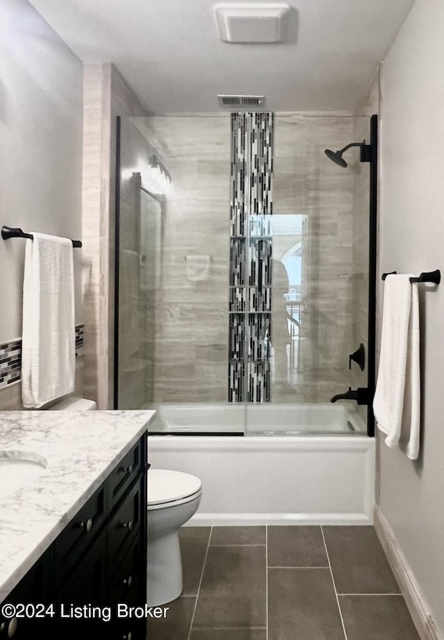 bathroom featuring toilet, vanity, baseboards, combined bath / shower with glass door, and tile patterned floors