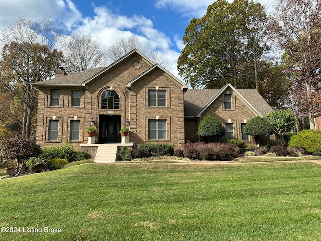 view of front of home with a chimney, a front lawn, and brick siding