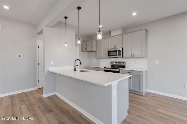 kitchen with decorative light fixtures, sink, backsplash, light hardwood / wood-style floors, and stainless steel appliances