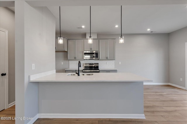 kitchen featuring sink, gray cabinetry, pendant lighting, stainless steel appliances, and decorative backsplash