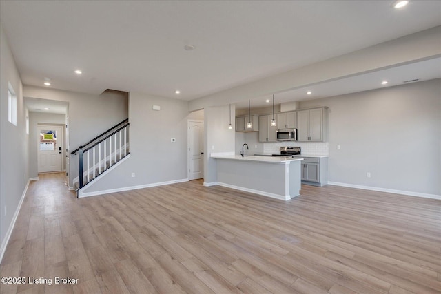 unfurnished living room featuring sink and light hardwood / wood-style flooring