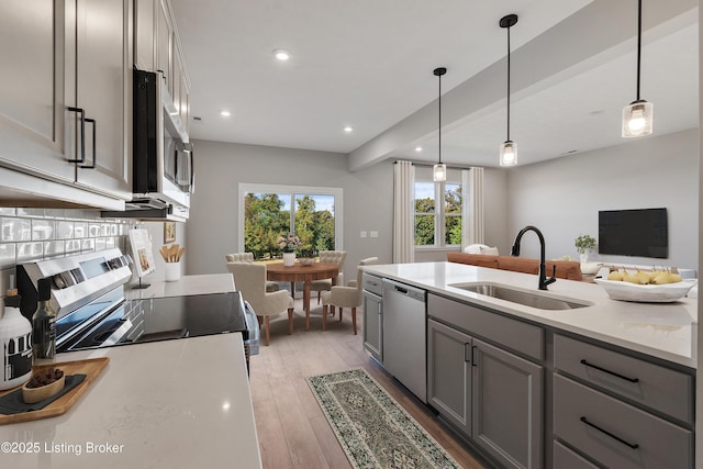 kitchen featuring light wood-style flooring, gray cabinets, a sink, light countertops, and appliances with stainless steel finishes