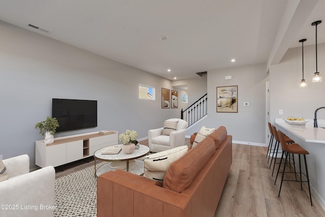 living area featuring light wood-type flooring, visible vents, recessed lighting, baseboards, and stairs