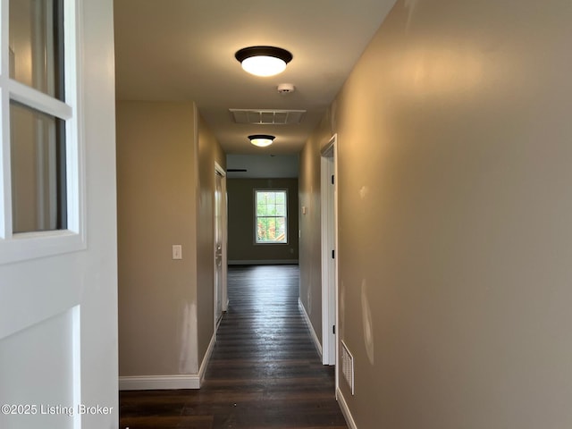 hall featuring baseboards, visible vents, and dark wood-type flooring