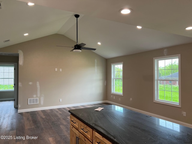 unfurnished room featuring a wealth of natural light, visible vents, dark wood-style floors, and vaulted ceiling