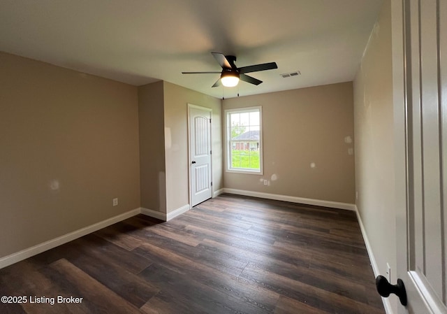 empty room with dark wood finished floors, baseboards, visible vents, and ceiling fan