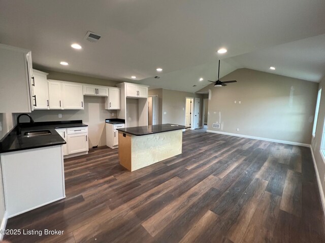 kitchen featuring white cabinets, a sink, dark countertops, dark wood-style floors, and recessed lighting