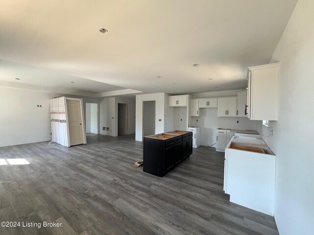 kitchen featuring white cabinets, dark wood-type flooring, washing machine and clothes dryer, and a kitchen island