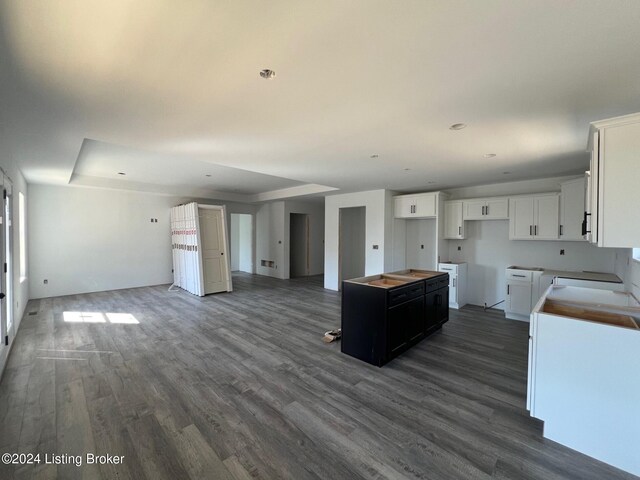 kitchen featuring dark wood-type flooring, a center island, white cabinets, and a raised ceiling