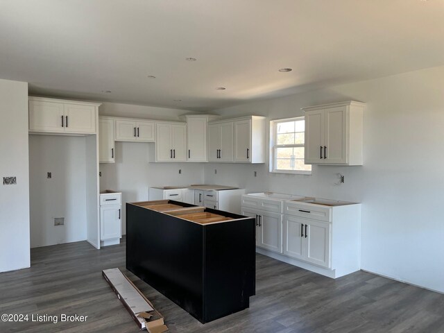 kitchen with white cabinetry, a center island, and dark wood-type flooring