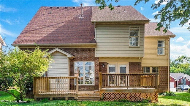 rear view of property with a wooden deck, roof with shingles, and brick siding