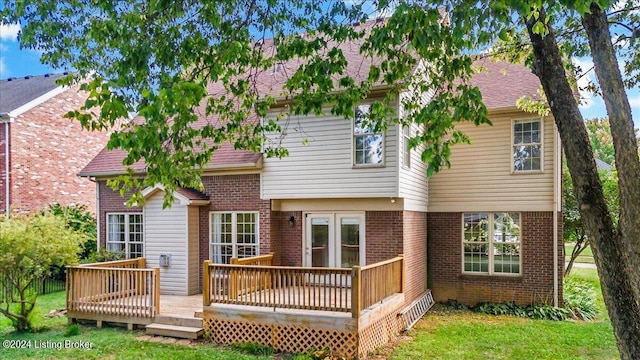 back of house featuring brick siding, a shingled roof, and a wooden deck