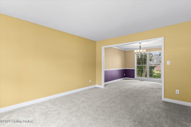 unfurnished room featuring baseboards, carpet floors, ornamental molding, and a notable chandelier