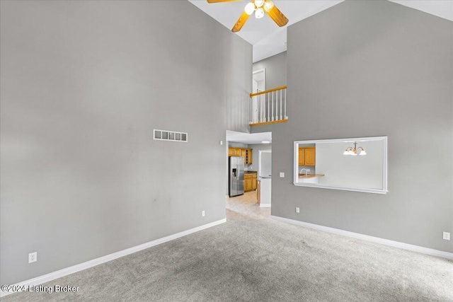 unfurnished living room featuring ceiling fan with notable chandelier, visible vents, baseboards, and light colored carpet