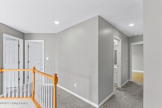 hall featuring recessed lighting, baseboards, light colored carpet, and an upstairs landing