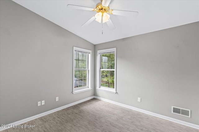 spare room with lofted ceiling, visible vents, ceiling fan, and baseboards