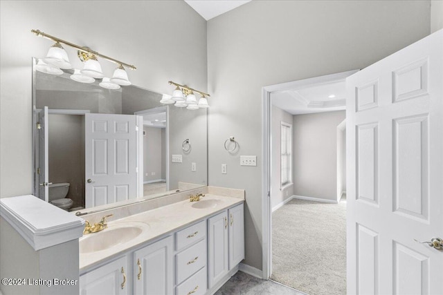 bathroom with double vanity, a sink, toilet, and baseboards