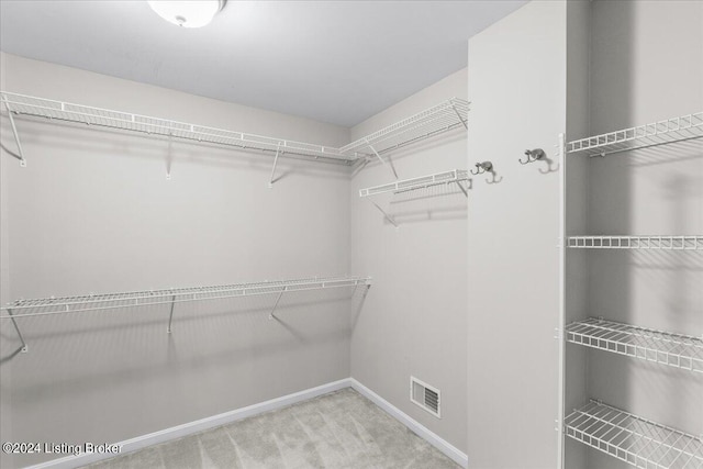 walk in closet with light colored carpet and visible vents