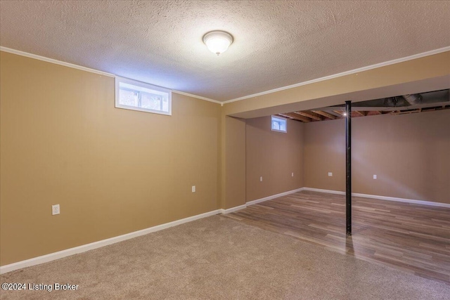 basement featuring baseboards, ornamental molding, and a textured ceiling