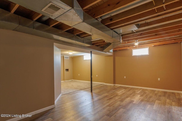 below grade area featuring wood finished floors, visible vents, and baseboards