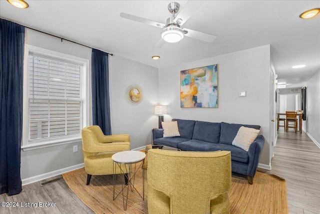 living area featuring baseboards, a ceiling fan, visible vents, and light wood-style floors