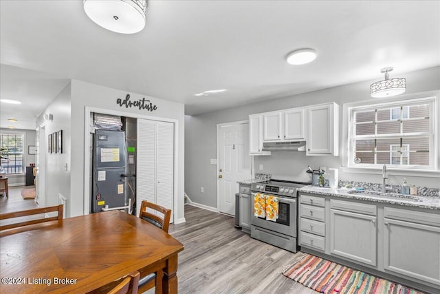 kitchen with white cabinets, stainless steel range with electric cooktop, a sink, light stone countertops, and under cabinet range hood