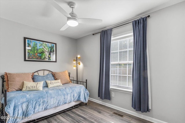 bedroom with a ceiling fan, wood finished floors, visible vents, and baseboards