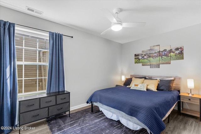 bedroom featuring ceiling fan, dark wood finished floors, visible vents, and baseboards